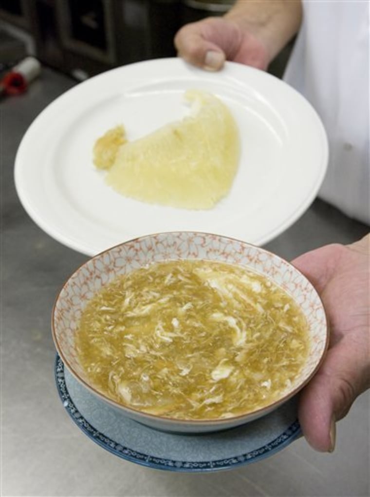Archie Chik, head chef at Kirin Restaurant in Honolulu, holds a bowl of shark fin soup and a plate with a shark's fin on Wednesday.